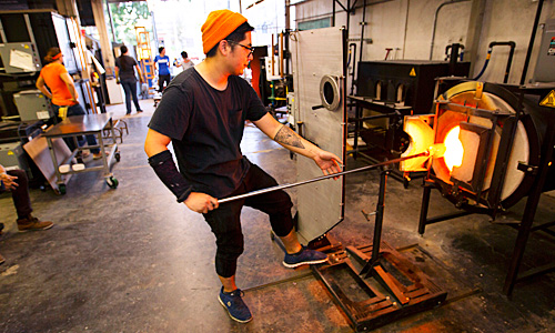Student pulling glass work from furnace